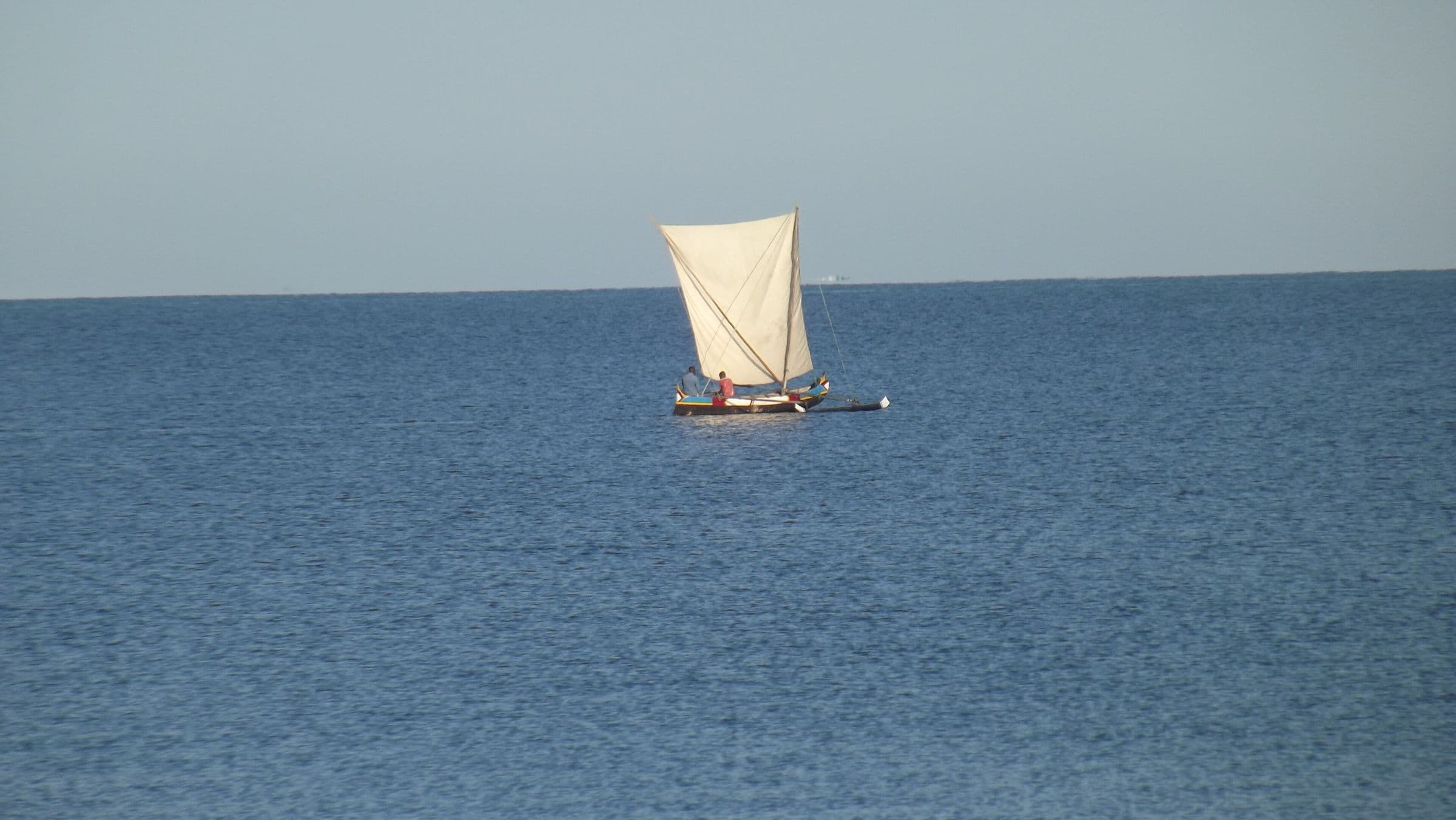 Pirogue à voile seule sur la mer calme, au large